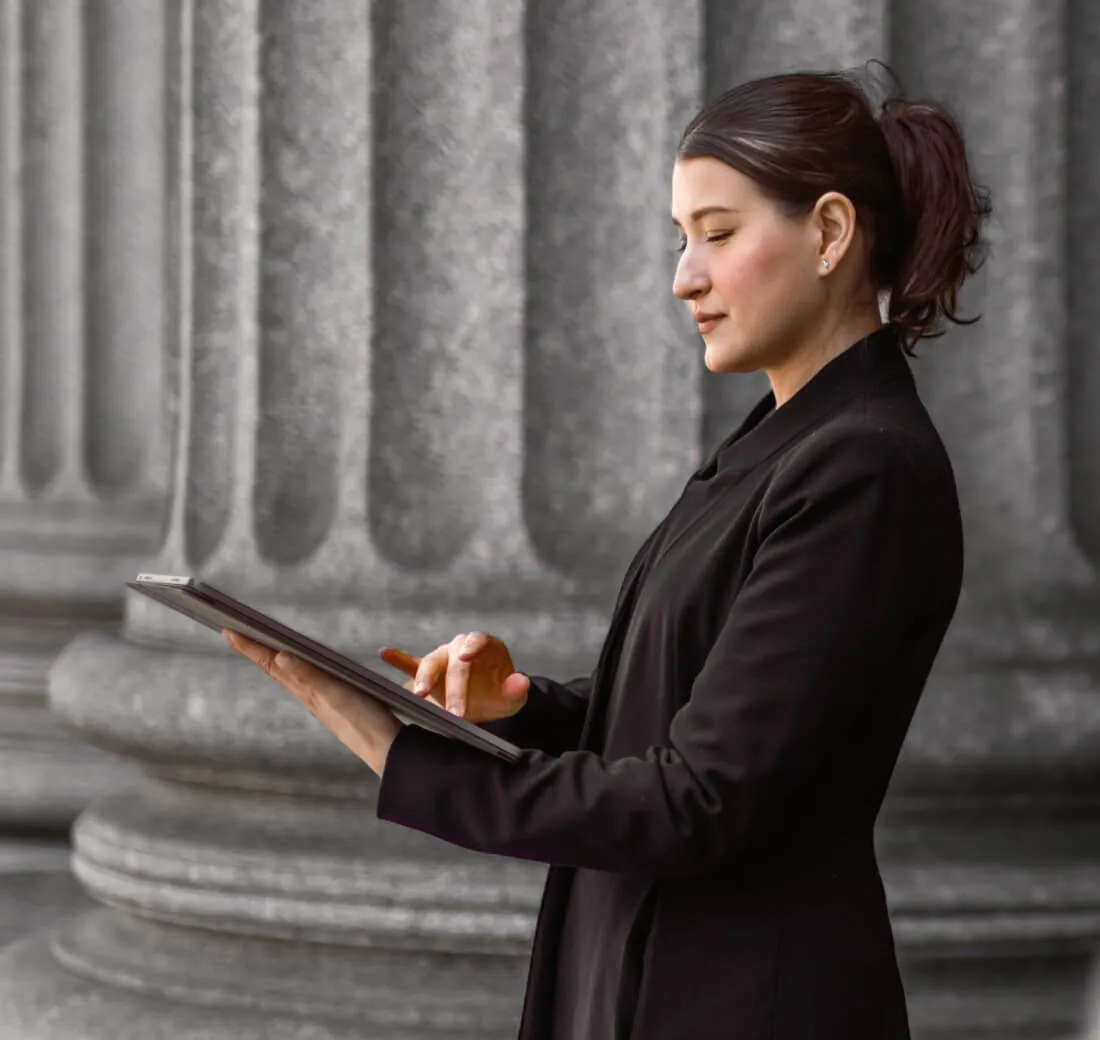 A woman checking her tablet in front of a government building