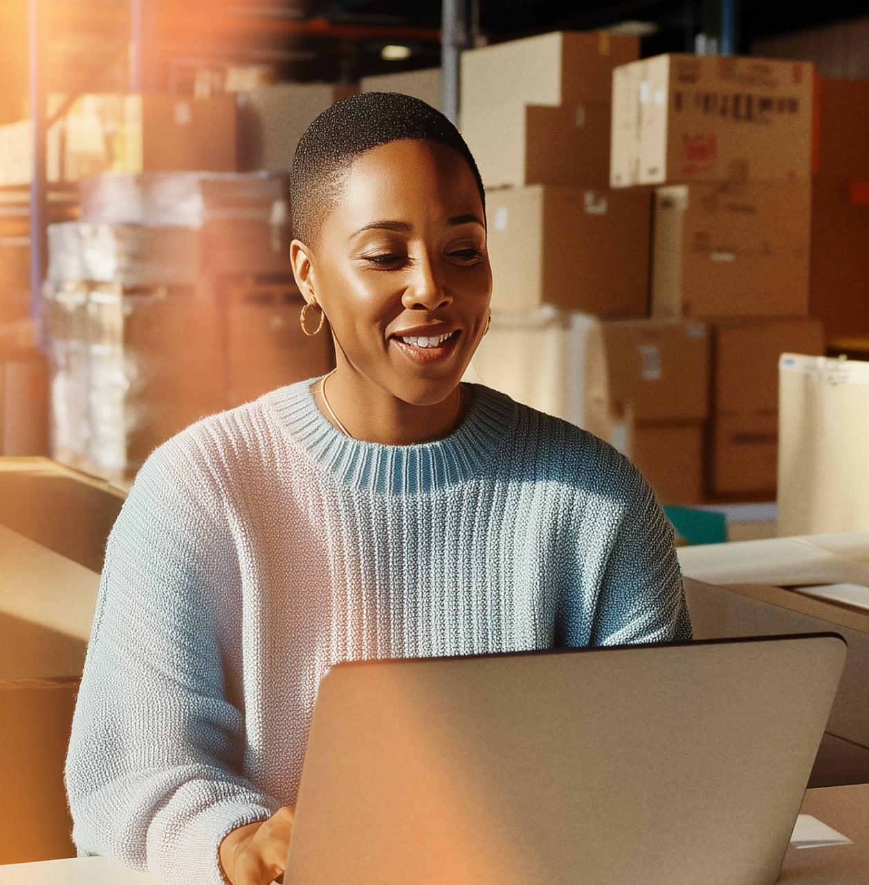 A woman on a laptop sitting inside a warehouse