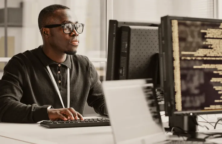 A male programmer typing on his keyboard while looking at his monitor