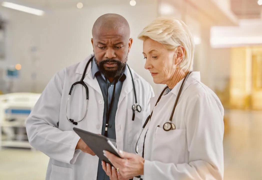 Two medical providers assess patient chart on a tablet